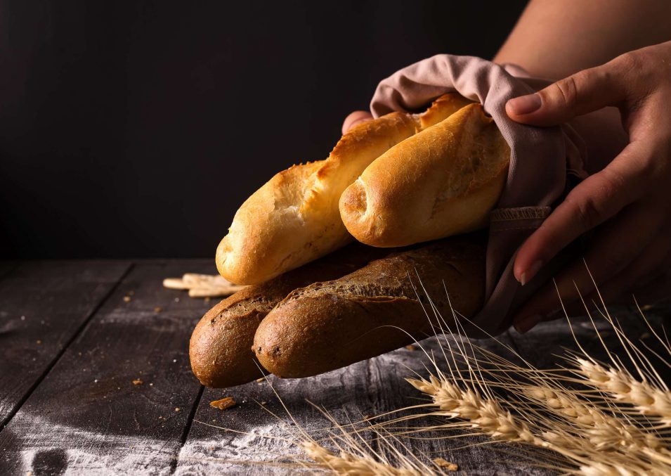 woman-holding-tasty-fresh-bread-sorts-on-a-dark-WY3X8GD-scaled.jpg